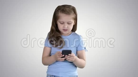 小可爱的女孩惊讶于梯度背景下移动智能手机上的有趣信息视频的预览图