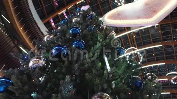 从底部看到高高的圣诞树上面装饰着蓝银球和五颜六色的花环视频的预览图