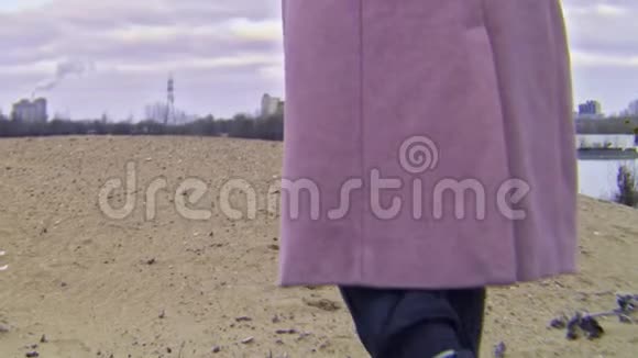 穿着秋靴的女人在沙滩上散步的特写镜头库存录像美丽的年轻女子在多云的沙滩上散步视频的预览图