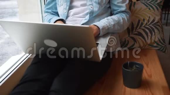 女孩在咖啡馆的窗户前的笔记本电脑上工作年轻漂亮的商业女人坐在黑暗的咖啡馆里努力工作视频的预览图