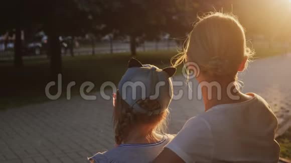 一个带着孩子的女人坐在公园的长凳上路人正在路过视频的预览图
