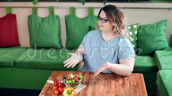 美丽的胖女人在厨房里享受健康的新鲜食物蔬菜沙拉高角度视频的预览图