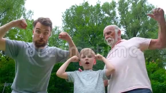 一个幸福家庭的肖像爷爷爸爸和他的儿子微笑着在公园里展示他们的肌肉背景视频的预览图