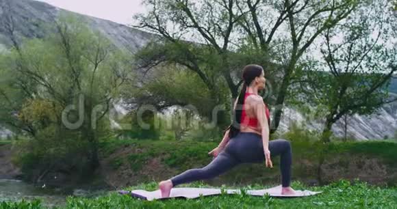 伸展姿势在垫子上适合女士练习瑜伽同时享受周围的风景和新鲜空气视频的预览图