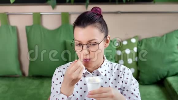 中度特写快乐的年轻臀部女士用勺子吃天然的新鲜奶油酸奶甜点视频的预览图