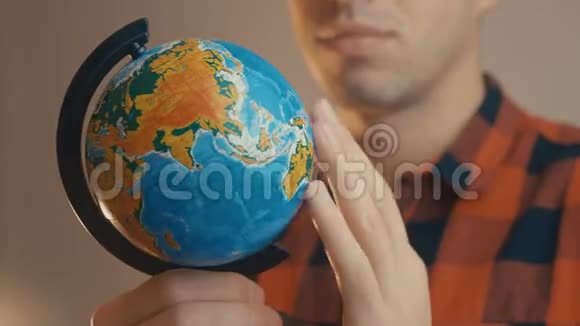 年轻男性持有地球仪一个人旋转一个地球仪并指向它旅行概念视频的预览图