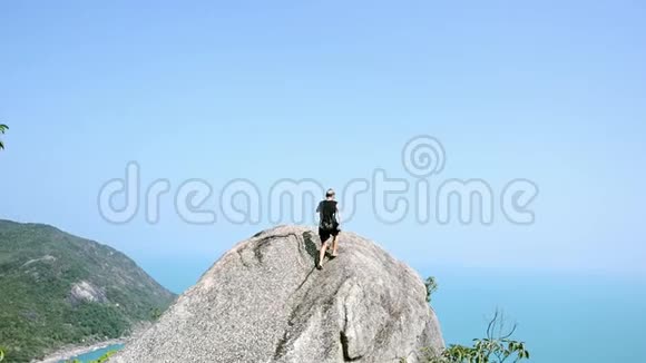 一位留着短发的年轻女子正在攀登岩石到悬崖边上视频的预览图