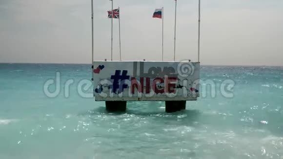 我爱尼斯欢迎标志码头就在尼斯法国海滩上美丽的蓝色波浪再次撞击视频的预览图