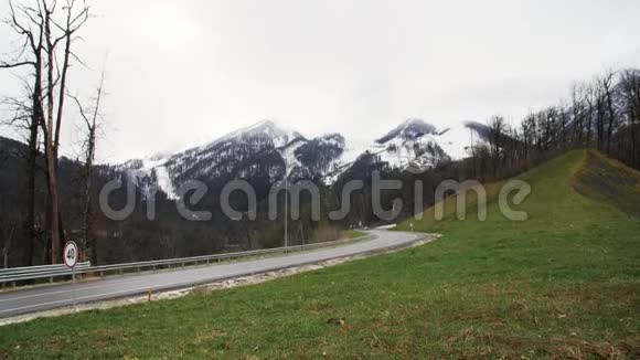 孤独的车在山路上开着雪山和多云的天空背景库存录像山路汽车旅行视频的预览图