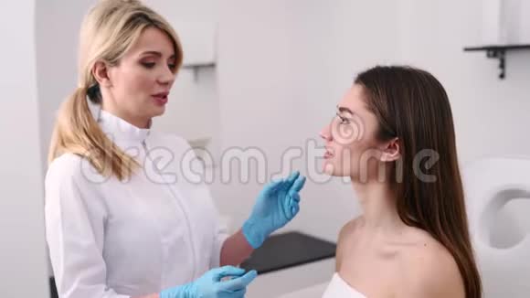 整形医生或美容专家检查妇女的脸用手触摸检查愈合后的皮肤视频的预览图