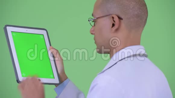 使用数码平板电脑近距离观看快乐秃顶多民族医生视频的预览图