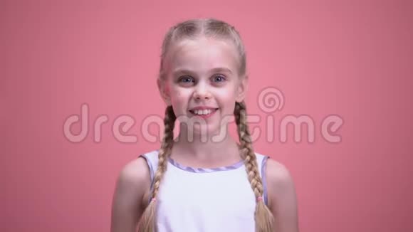 微笑的小女孩带着辫子在镜头特写时展示玩具的心慈善组织视频的预览图