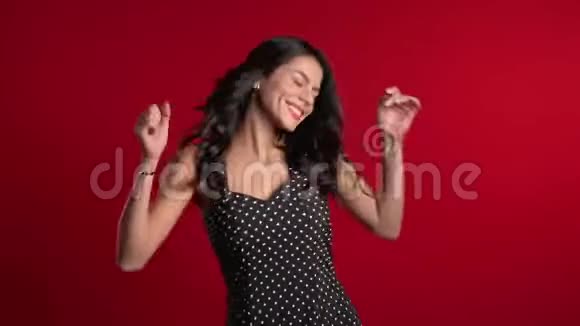漂亮的拉丁女孩穿着红色背景的裙子微笑着跳舞心情很好幸福党性观念视频的预览图
