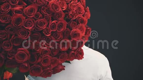 一个英俊的男人肩上捧着一大束玫瑰背对着镜头转过身来微笑着视频的预览图