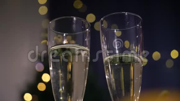 两杯香槟在圣诞节或新年花环的背景下闪闪发光的葡萄酒假日灯视频的预览图