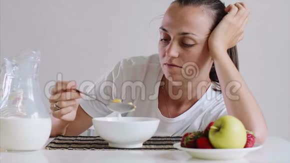 困乏的年轻女人不想吃她的早餐玉米片和牛奶视频的预览图