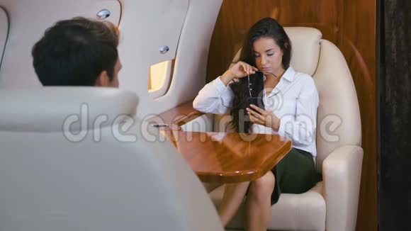 漂亮的商务女性戴着眼镜手里拿着智能手机乘坐私人飞机旅行商务旅行视频的预览图