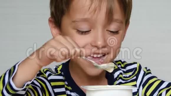 可爱的男孩欧洲的外观是酸奶一个快乐的孩子坐在桌子旁的肖像埃科婴儿食品视频的预览图