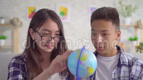 年轻的积极的亚洲夫妇手里拿着地球仪计划一次旅行视频的预览图