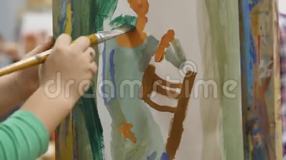 年轻的艺术家的手小男孩艺术家用画笔描绘画布坐在桌子上画画布程序视频的预览图