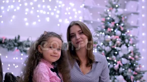 年轻貌美的母女俩抱着拥抱看着镜头微笑着面对圣诞节视频的预览图