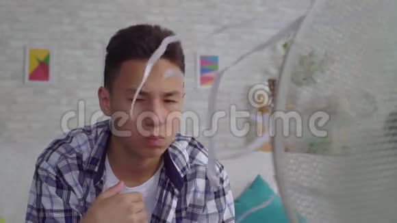 悲伤的亚洲青年男子从坐在一个工作风扇前的炎热中得救视频的预览图