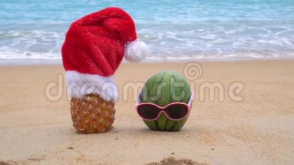 在热带海滩上菠萝戴着圣诞老人的帽子和戴着太阳镜的绿色欢快的西瓜新年和圣诞节视频的预览图
