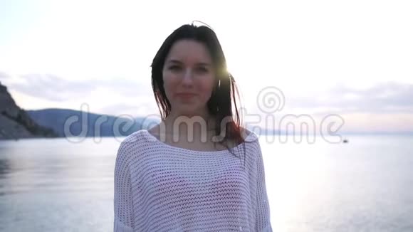 美丽的黑发女孩站在大海的背景下的阳光下视频的预览图