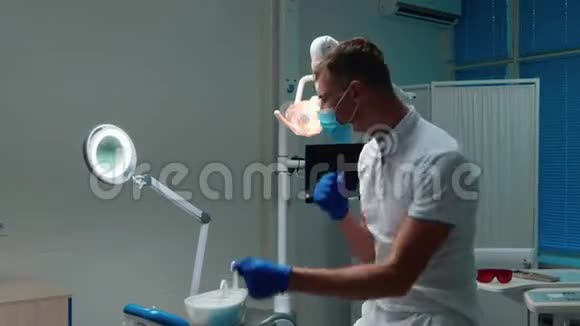 有趣的年轻英俊的牙医在工作场所附近情绪激动地跳舞戴着医疗手套和口罩视频的预览图