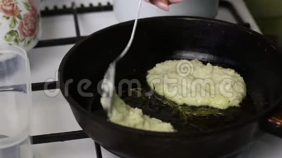 女人炸煎饼一个女人把土豆泥放在热锅上附近躺着一枝迷迭香视频的预览图