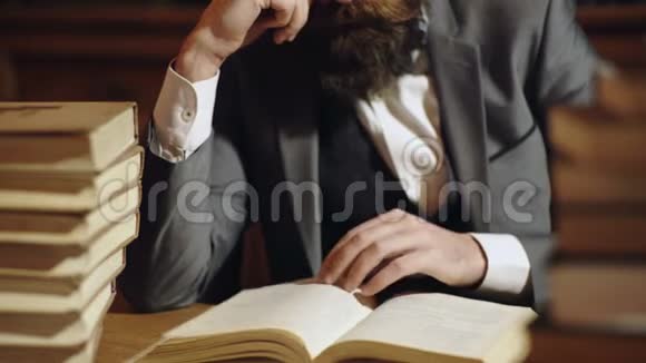 白人男性阅读翻书页一堆书在桌子上有胡子的人在木桌上看书视频的预览图