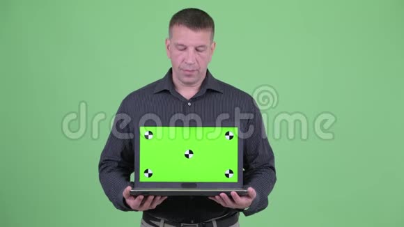 一个成熟的商人一边说话一边展示笔记本电脑视频的预览图