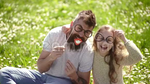 儿童和父亲在草地上用眼罩拍照聪明又聪明的概念爸爸和女儿坐在一起视频的预览图