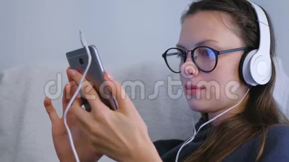 女人正在浏览和寻找社交媒体在智能手机眼镜和耳机视频的预览图