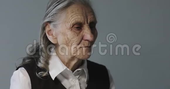 一位满脸皱纹的老妇人正在吃早餐看着一台笔记本电脑视频的预览图