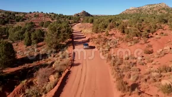 越野车在尘埃落定的乡村道路上穿越红沙沙漠的空中景观视频的预览图