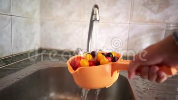 手拿着一个带有新鲜水果和浆果的香菜用水在厨房里洗视频的预览图