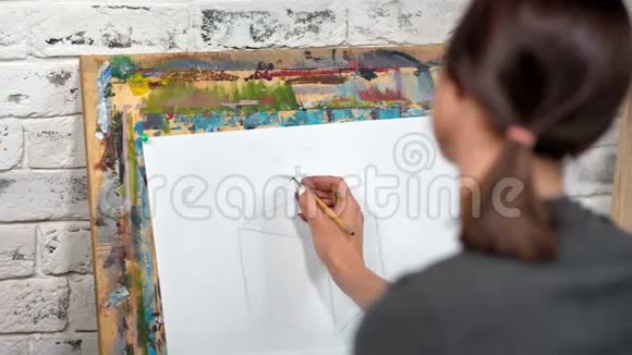 画家用灰色铅笔在画布上画素描特写后视视频的预览图