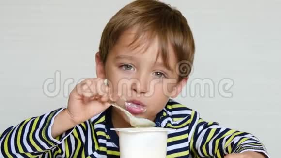 一个可爱的小男孩坐在桌子旁吃酸奶体验快乐快乐和乐趣孩子视频的预览图