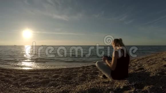 海滩上的女孩坐着一块平板电脑视频的预览图