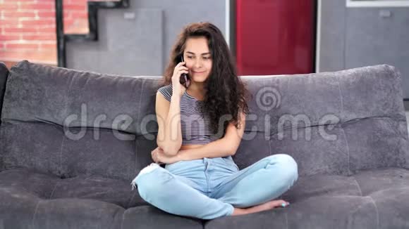 微笑混合种族年轻的非正式女人在家里用智能手机聊天视频的预览图