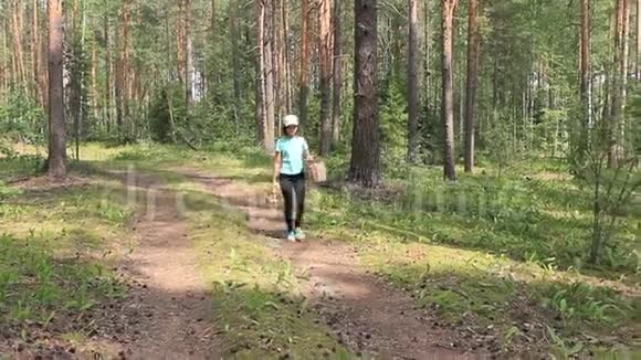 女孩带着两个篮子沿着森林小径散步视频的预览图