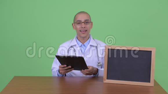 快乐的秃头多民族医生用剪贴板解释一些事情视频的预览图