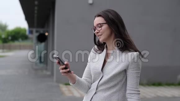 一个穿着商务服的年轻女人在电话上读到一条信息微笑着一个戴眼镜的女商人视频的预览图