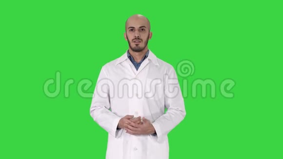 穿着医用外套的阿拉伯医生用手在绿色屏幕上展示一些东西Chroma键视频的预览图