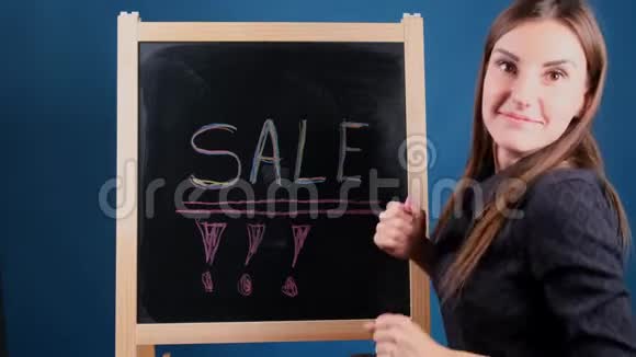 题词SALE写在黑板上一个快乐的女孩正在附近跳舞等待折扣视频的预览图