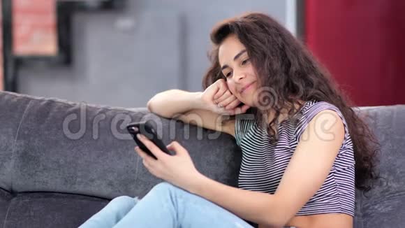 一位年轻貌美的女士她喜欢在家玩智能手机聊天视频的预览图