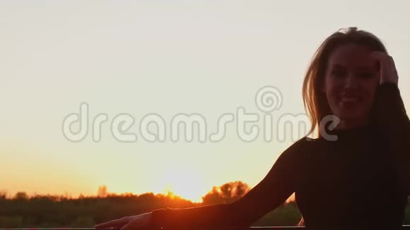 夕阳下美丽的女孩摇动她的头发在空中飞舞视频的预览图