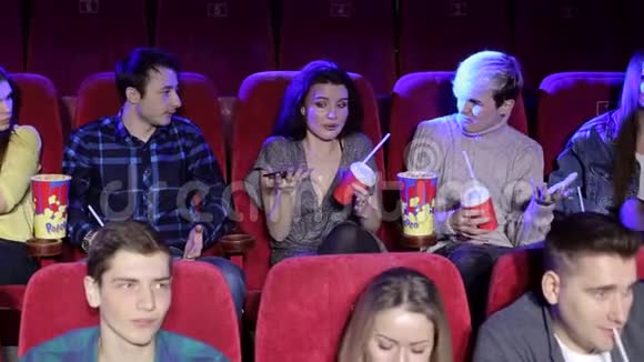 粗鲁的年轻女子在电影院看电影时用手机说话视频的预览图