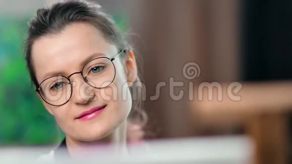 年轻漂亮的女画家戴着眼镜欣赏绘画视频的预览图